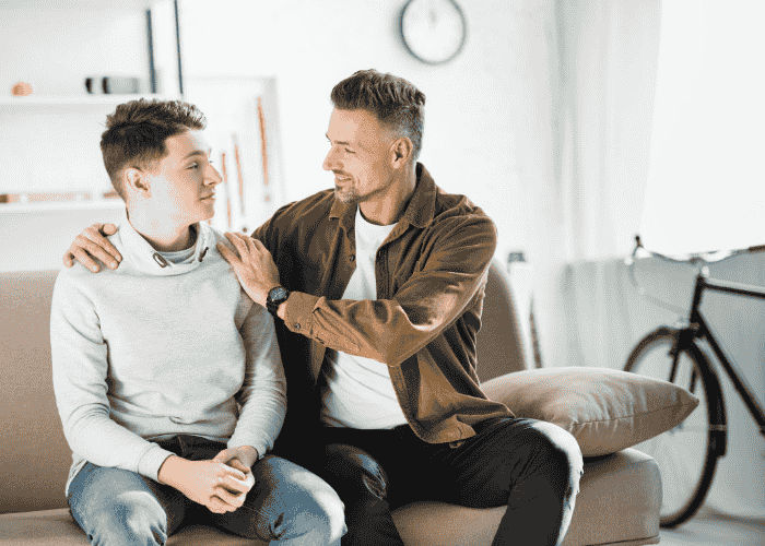 Father with his hands on his son's shoulders in pride after son receives treatment for teen mistrust in adults