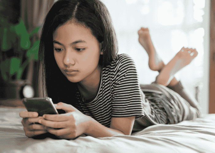 Teenage girl looking unhappy while on her phone due to social comparison