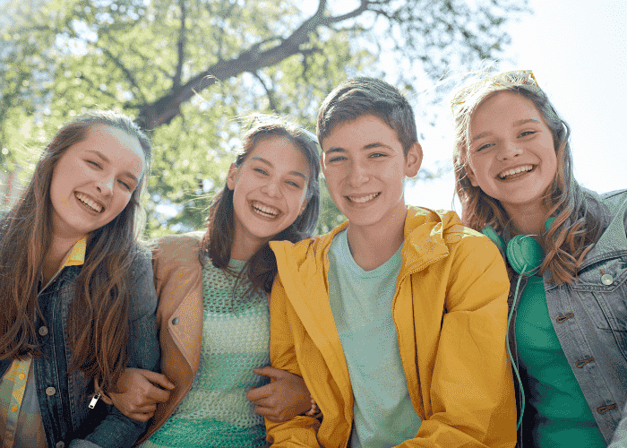 Four teenage friends smiling due to treatment for anxiety-related pins and needles in teens