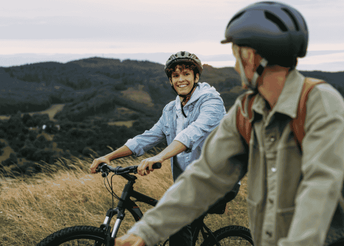 Teen boy on mountain bike ride with dad smiling after seeking support from The Holman Group insurance coverage