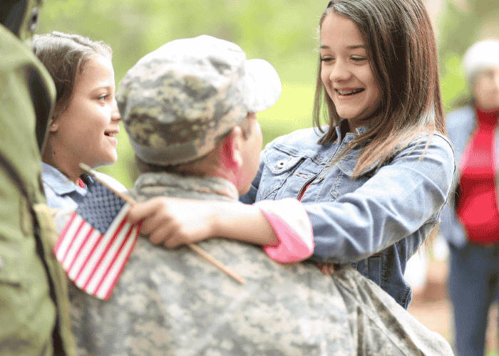 teen girl smiling and hugging veteran dad after seeking support with TRICARE Mental Health Coverage