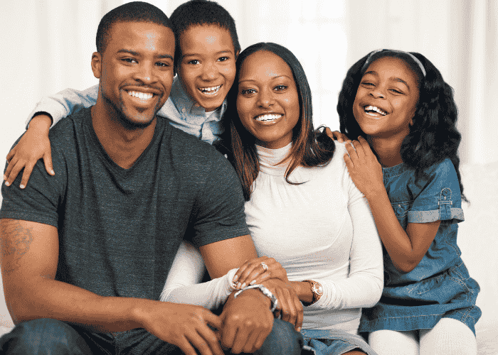 Teen girl with mom, dad and brother, smiling after seeking support with ComPsych mental health insurance