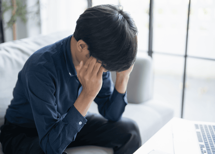 teen boy sat of sofa with laptop on coffee table with his hands on his head looking anxious about Employers Health Network (EHN) Coverage