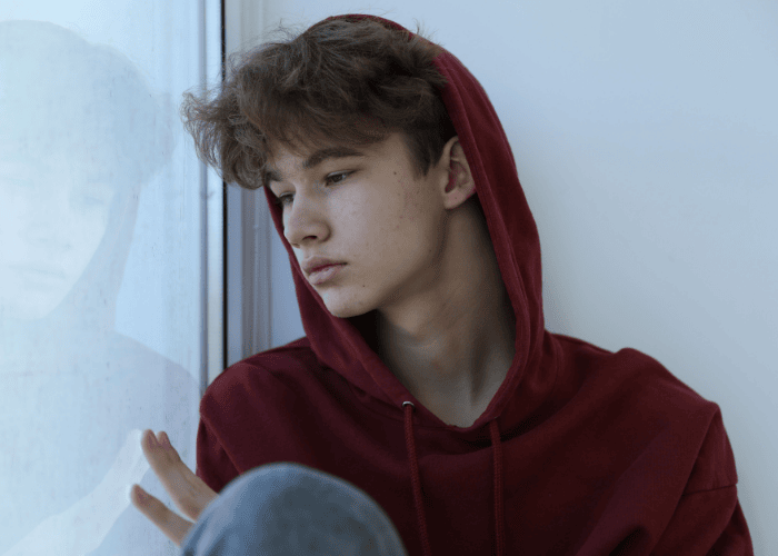 teen boy sitting by window experiencing neurodiversity and mental health in teens