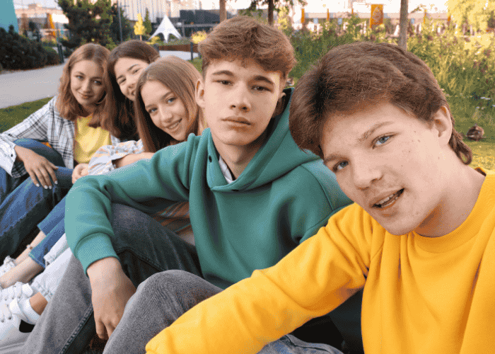 teen boy sitting with friends in the park after support with understanding limerence in teens
