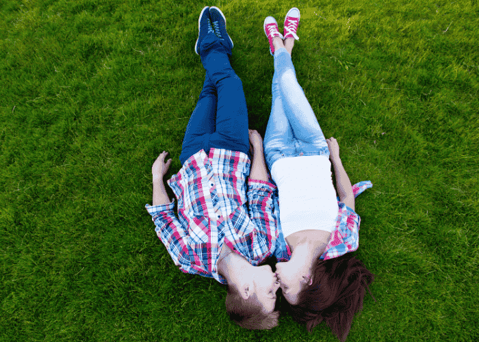 Teen couple laying on grass in park kissing needing support with limerence vs. love in teens
