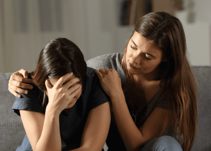 mom sitting next to upset teen daughter comforting her and considering seeking support with HMC HealthWorks