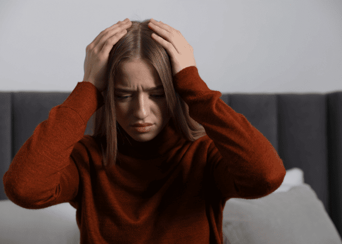Teenage girl in distress with her hands on her head due to autistic burnout vs. depression