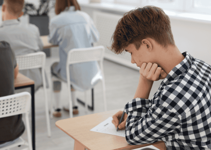 Teenage boy sat in at desk needing support with mental health in the classroom