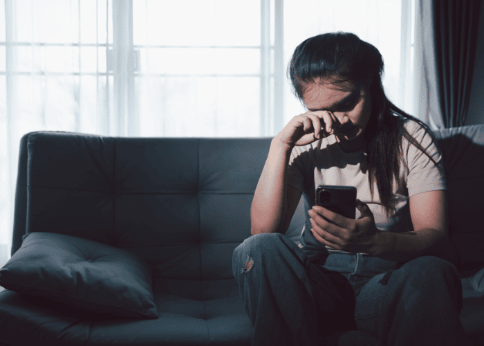 Teenage girl looking at phone needing support with ways to cope with global events