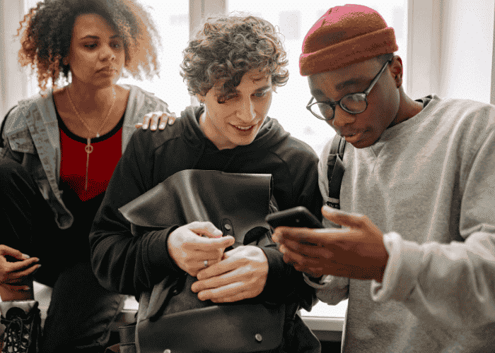 Teenage boy looking at his phone with friends after support with ways to cope with global events