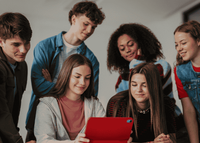 Group of teenagers looking at tablet together after support for teen mental health and social media
