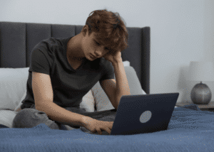teenage boy looking at news on laptop needing support with how to protect youth mental health