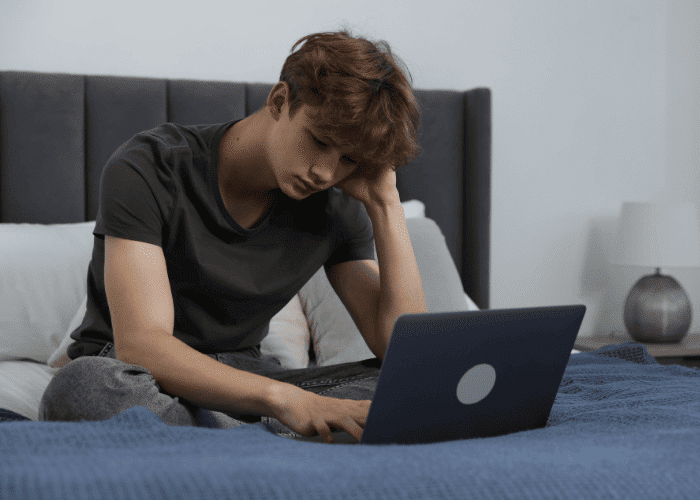 teenage boy looking at news on laptop needing support with how to protect youth mental health