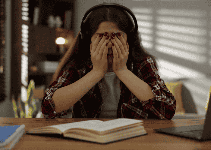 Teenage girl with her face in her hands recognising how everyday stress affects teens with childhood trauma