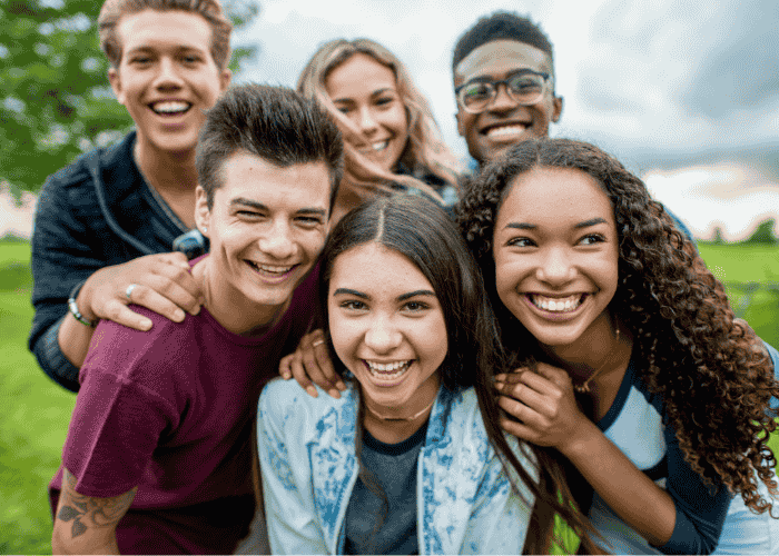 Group of teenagers smiling after having treatment for developmental trauma in teens