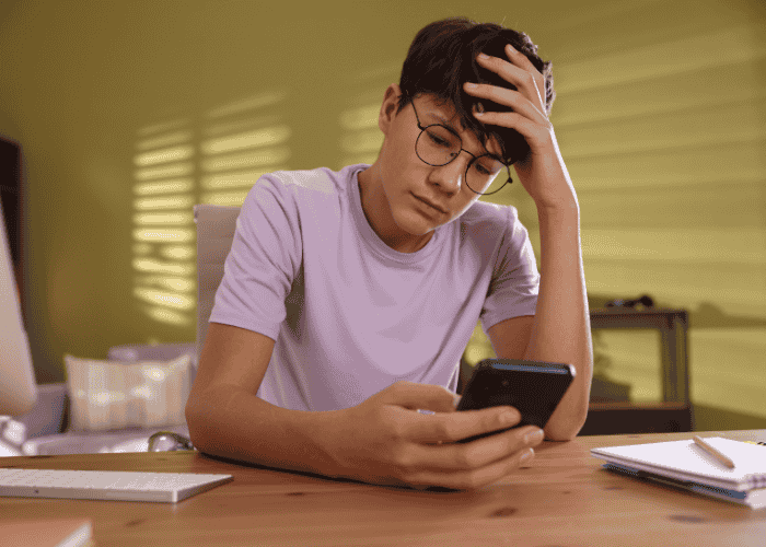 Teenage boy looking at his phone wondering how social exhaustion affects neurodivergent teens