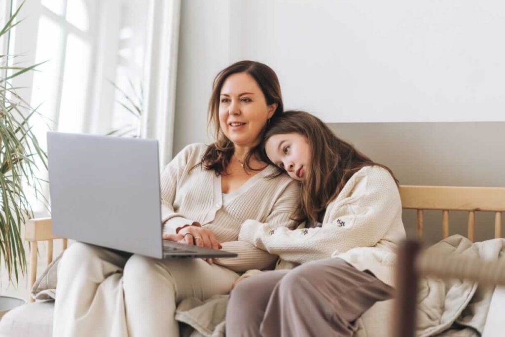 Mother and daughter sitting next to each other looking at a computer
