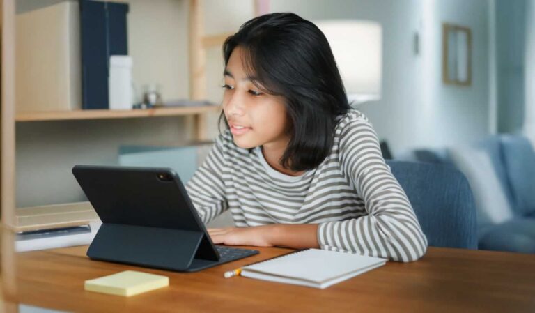 Teen girl sitting at table looking at tablet device