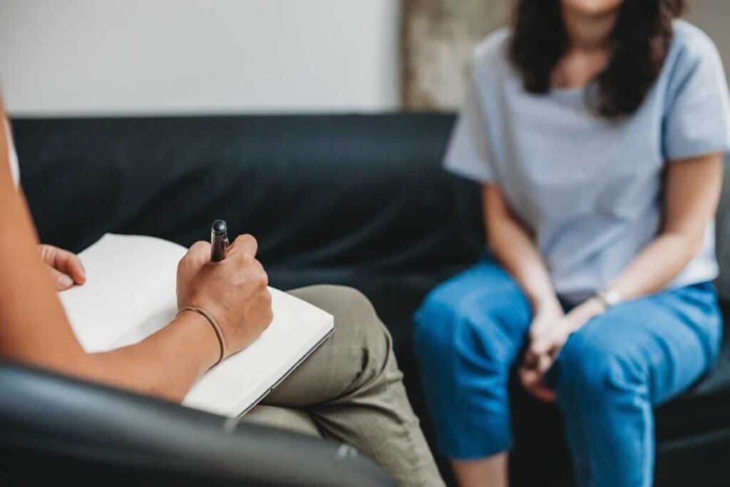 Woman sitting on couch talking to therapist who is sitting across the way on a chair