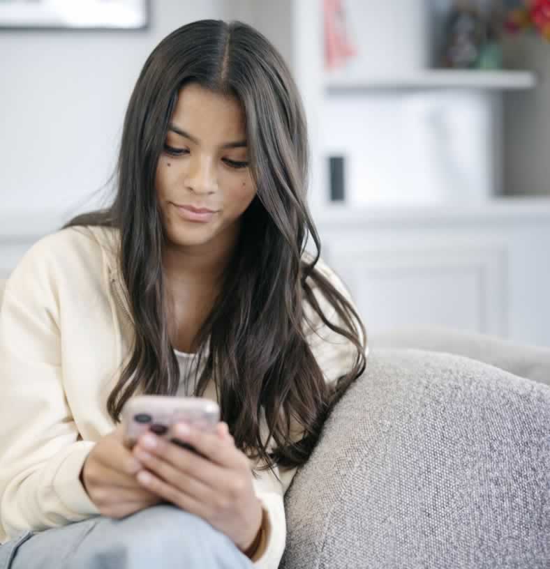 Female teen sitting on couch looking at her cell phone