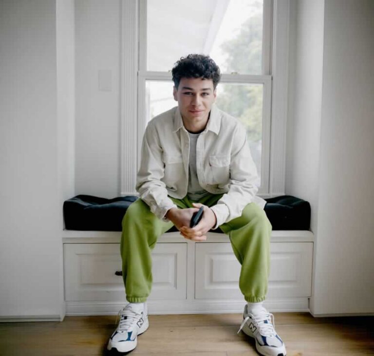 Young man sitting on window seat with phone in hands