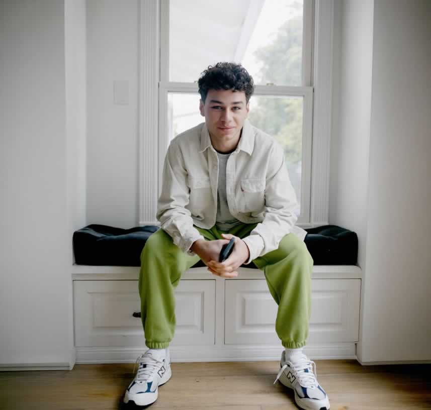 Young man sitting on window seat with phone in hands