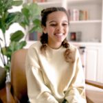 Young female teen sitting in chair smiling as she starts therapy appointment
