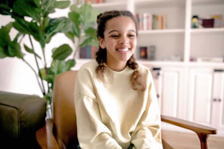 Young female teen sitting in chair smiling as she starts therapy appointment
