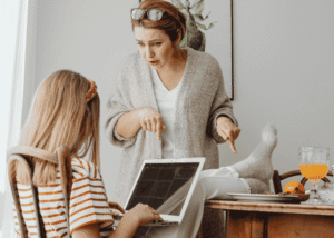 Mom angry at teen daughter sitting with feet on the table needing support with parent-teen conflict