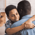 Teen boy hugging dad smiling after support with parent-teen conflict