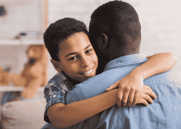 Teen boy hugging dad smiling after support with parent-teen conflict