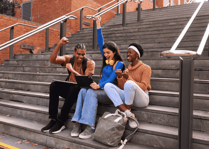 Teens sitting on steps outside listening to music in group and smiling after support with youth loneliness