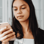 Teen girl looking at cellphone needing support with how to use social media to improve teen mental health
