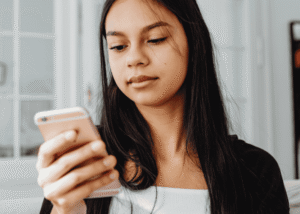 Teen girl looking at cellphone needing support with how to use social media to improve teen mental health
