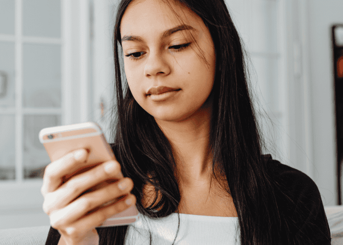 Teen girl looking at cellphone needing support with how to use social media to improve teen mental health