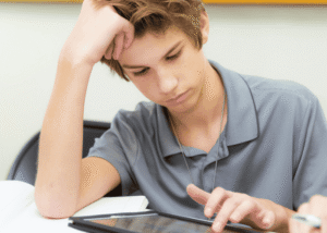 Teen boy using tablet with head in hand needing support with AI and teen mental health