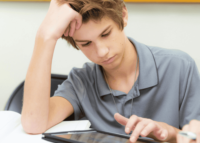 Teen boy using tablet with head in hand needing support with AI and teen mental health