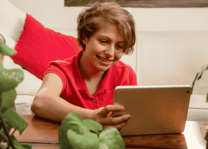 Teen looking at laptop smiling after support with digital literacy and teen mental health