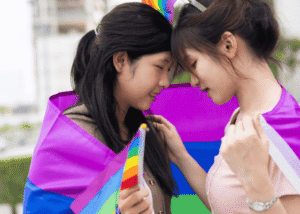 Teen girls wrapped in pride flag wanting support with LGBTQ+ teens mental health