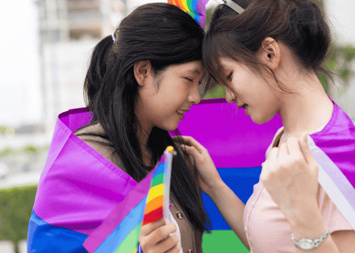 Teen girls wrapped in pride flag wanting support with LGBTQ+ teens mental health