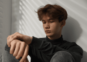 Teenage boy sitting against wall needing support through California's Executive Order