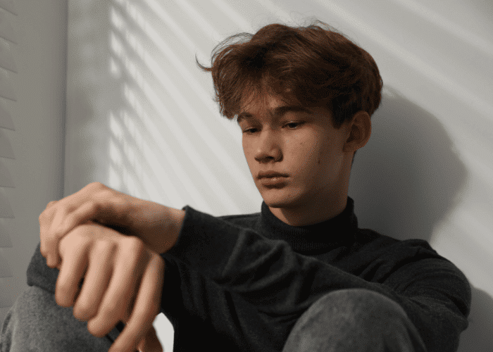 Teenage boy sitting against wall needing support through California's Executive Order