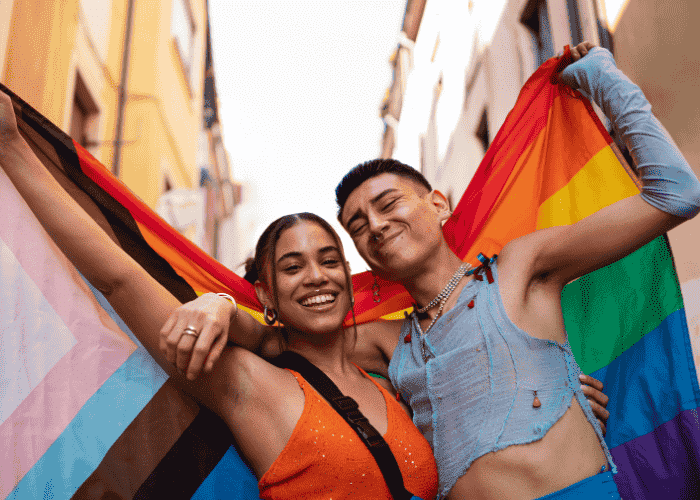 Teens holding pride flag smiling after support with LGBTQ+ teens mental health