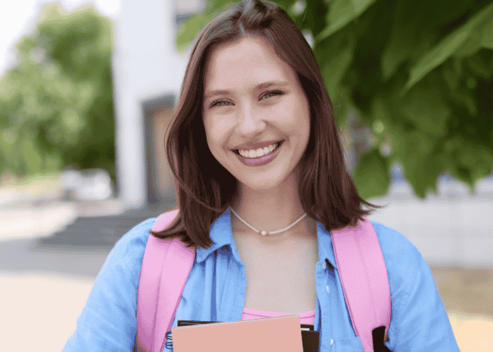 Teenage girl outside school holding books smiling after support with new laws in Virginia