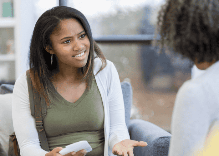 Mom sitting opposite angry teen daughter needing support with parenting style