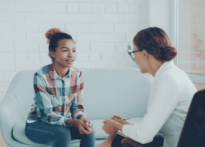 Teen girl sitting in therapy session after seeking support for the downside of resilience in teen mental health