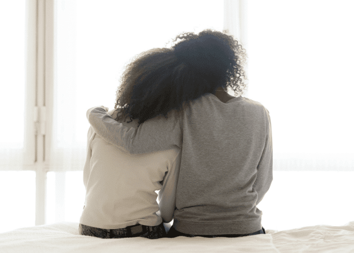 Teen girl sitting on bed with mom after support with choosing the right residential program