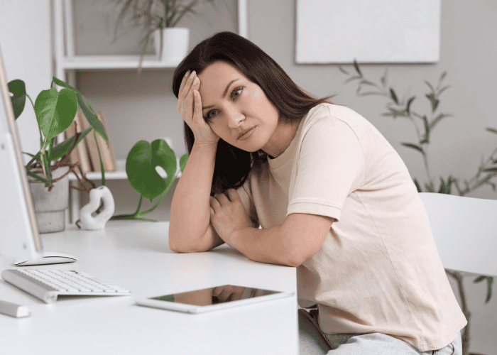 Mom sitting at desk with head in hand worrying what questions to ask residential providers