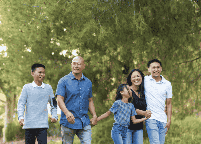 Mom and dad walking outside with teen children smiling after support with what questions to ask residential providers